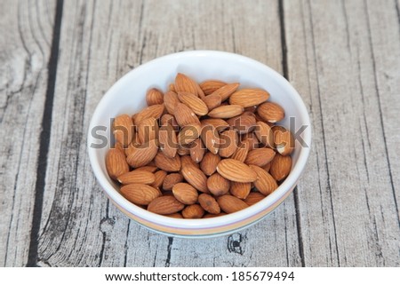 Roasted almonds in a porcelain bowl on a wooden background