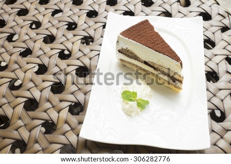 tiramisu cake served with whipped cream in the white dish