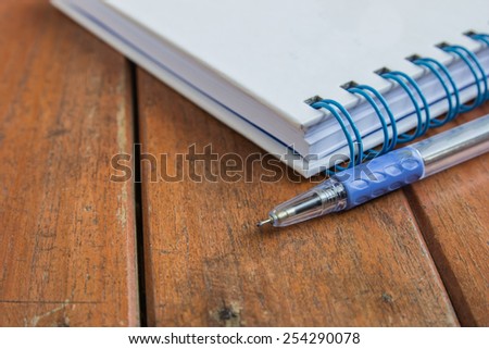 pen and the book on wooden table