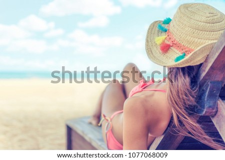 Young woman whit sun hat relaxing on sun bad enjoys sunbath at the beach with the sea and horizon in the background on hot summer day travel and tourism concept