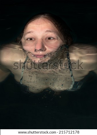 Head of a woman close up floating in water on a black background