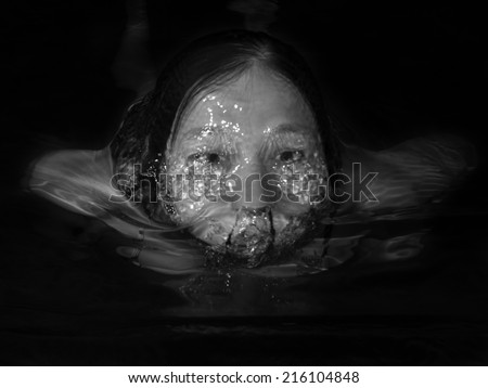 Monochrome image of a woman floating in water on a black background