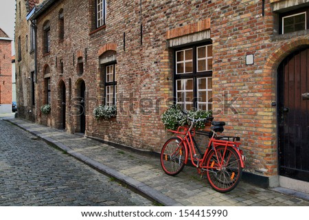 Red bicycle near the window of brick house in Brugge, Belgium.