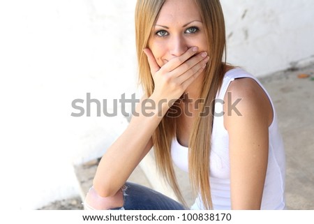 Young blonde woman cover mouth with hand closeup
