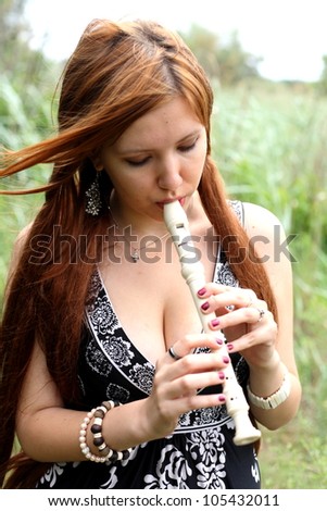 Close-up portrait of beautiful young woman playing flute, outdoors