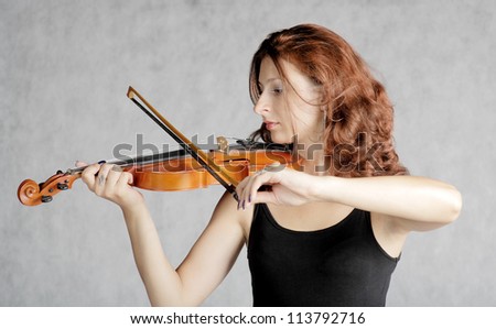 Beautiful violinist redhead woman on gray gradient background