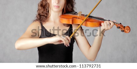 Beautiful violinist redhead woman on gray background