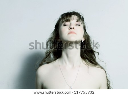 beautiful girl with with curly hair nude shoulder looking up with golden chain on the neck toned image
