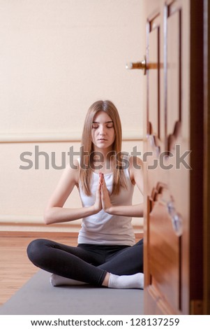 Pretty blonde women meditating in yoga studio on beige background through the open door . Mental health spiritual development concept