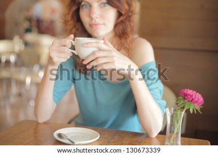 Redhead woman with curly hair drinking coffee from a cup very shallow depth of field