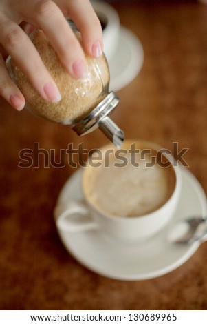 coffee cup on the table. Person pours sugar