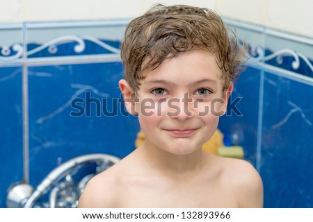 Smiling little boy in bathroom against a blue wall head and shoulders shot