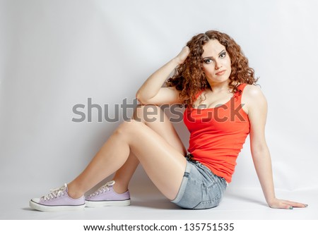 curly hair brunette on white background weared orange red shirt positive girl joy concept sitting side view