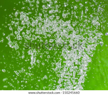 Levitating water drops. Water drops flying in the air on the grass-green background