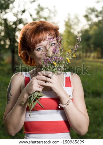 Young redhead woman in the park with flowers. Portrait a beautiful young woman with flowers in the forest . Casual photo on fresh nature background