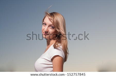 beautiful young woman on a background of clear sky side view looking at camera head nd shoulders shot