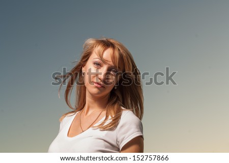 Front view of the beautiful young woman on a background of clear sky