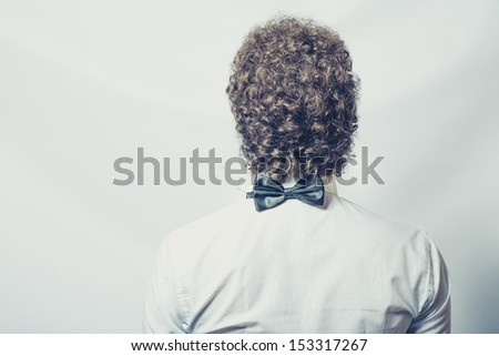back of the head and shoulders of the curly man with bow tie on the back of the neck  toned image