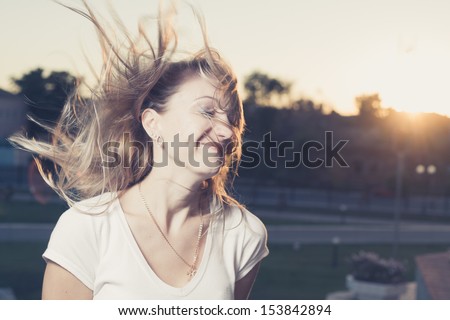 Blond hair fly in the wind at sunset, 20s women head and shoulders at dawn