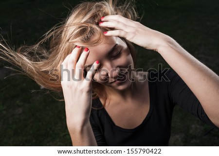 portrait of a girl on a windy day, hair fly in the air, touching head by hand