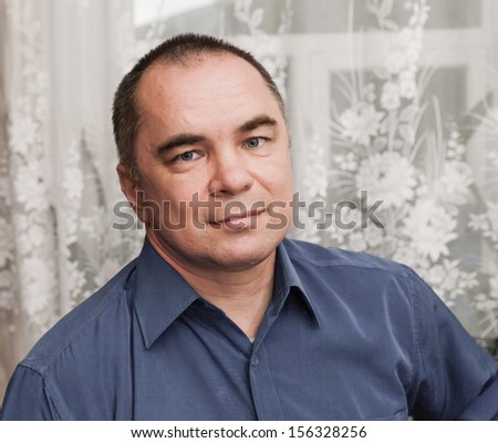 businessman weared blue shirt, mid age man, indoors, looking away , horizontal shot, looking at camera, angle view, toned desaturated image
