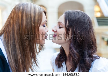 Scenic kiss. Female friends inside the mall. Multicultural friends.