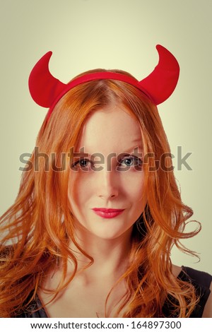 Vertical shot of redhead girl with red  horns looks like pretty Devil? isolated on white