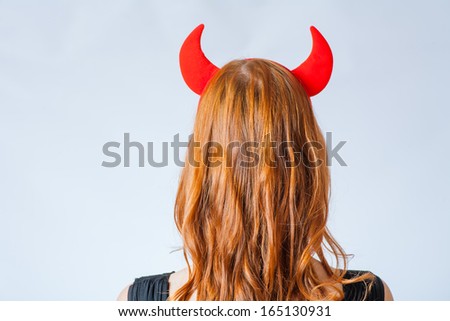 backview close up of a red haired girl with horns like a devil