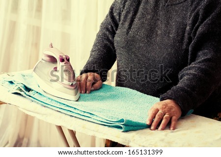 senior women iron clothes, mid section view