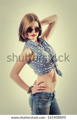 Sexy Rock Star Posing. 50s retro style girl weared jeans and round glasses. Vintage toned image