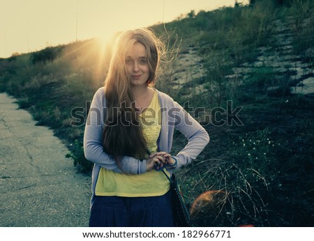 Cute blonde girl backlit by evening sun. Looking at camera. Front view