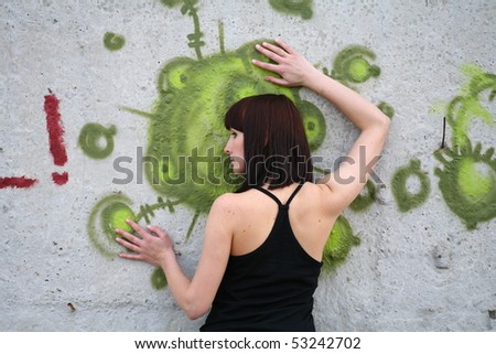 brunette girl posing against concrete wall with graffiti