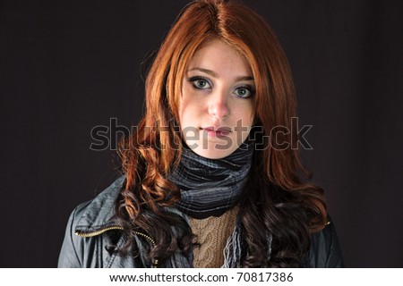 red hair young woman in a coat and scarf with a slight smile