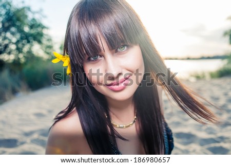Outdoor summer closeup portrait of young pretty fashion smiling woman with red lips and big eyes with sunflower in her hair