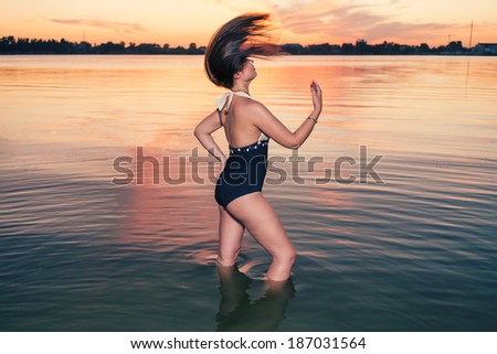 Retro fashion women dancing in water at sunset.
