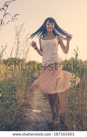 Girl dancing outdoors. Front view, toned image. Low light film photo, blurred motion