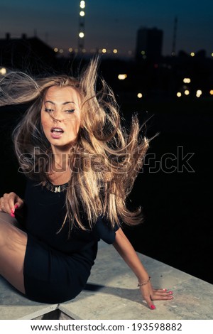Cute blonde sitting in a city park with her hair fly in a wind