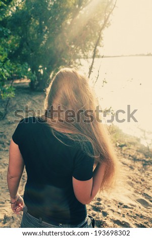 Rear view of a long haired women  on sandy coast