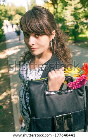 Women with hand bag and flowers outdoors vertical image