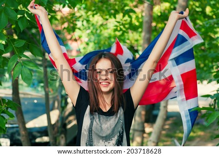 Young vivacious female with UK flag in her hans outdoors.