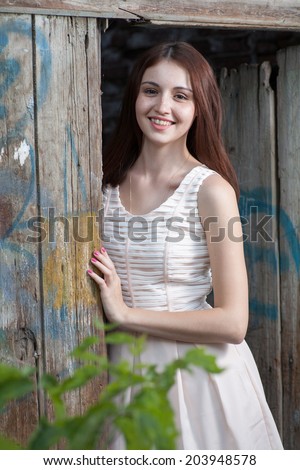 Young women smiling  while leaning at wood door. Cute girl looking out of aged wooden gates and looking positive