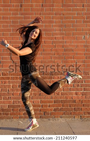 Street dancer girl. Sporty women dancing in the street against red brick wall in very happy state