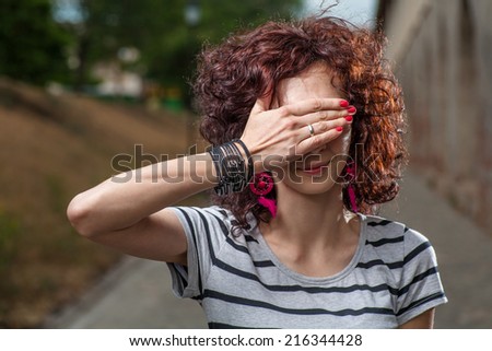 Redhead hide face with her hand outdoors