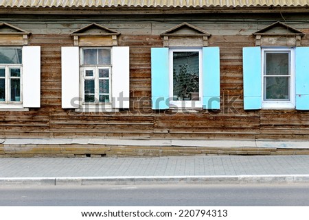 Wall of the aged wooden hut and fragment of pavement in Astrakhan, Russia. Four old vintage windows in traditional style. Front view, open shutters. Vintage window  and a lot of copyspace