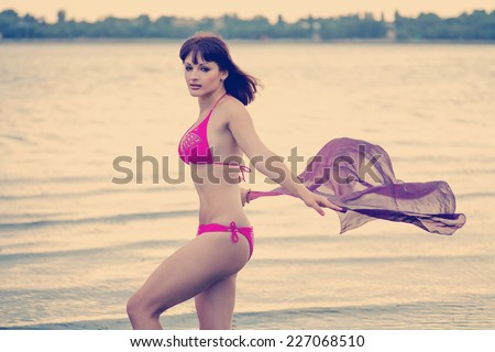 Freedom Concept. Beautiful Girl with Violet  Scarf standing in  the Water.  Beautiful Girl With  Light  Textile on The Beach. Travel and Vacation. Instagram colors