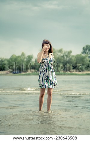 Women in water hide her face by her hand at windy day