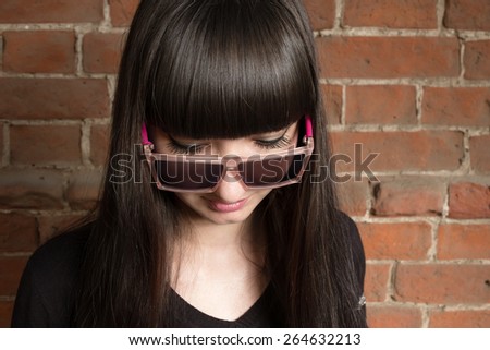 Young women head and shoulders shot looking down in trendy sunglasses