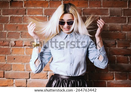 Young hipster girl in sunglasses  shaking her head, hair fly in the air