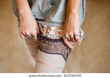 Tender undressing.  Girl in nightdress moving down her tights