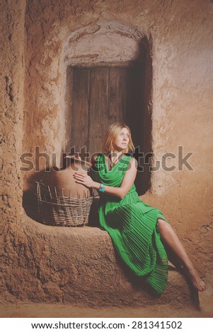 Women slave posing with big pot near door of ancient oriental home